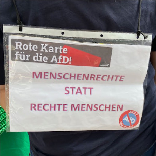 Foto Demoschild. Text: Rote Karte für die AfD: Menschenrechte statt rechte Menschen